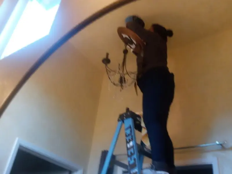 Electrician installing a chandelier in a Winchester residence